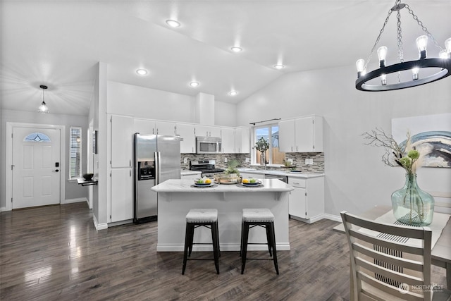 kitchen featuring white cabinets, a center island, vaulted ceiling, pendant lighting, and appliances with stainless steel finishes