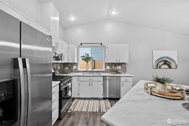 kitchen featuring stainless steel appliances, decorative backsplash, lofted ceiling, white cabinets, and sink