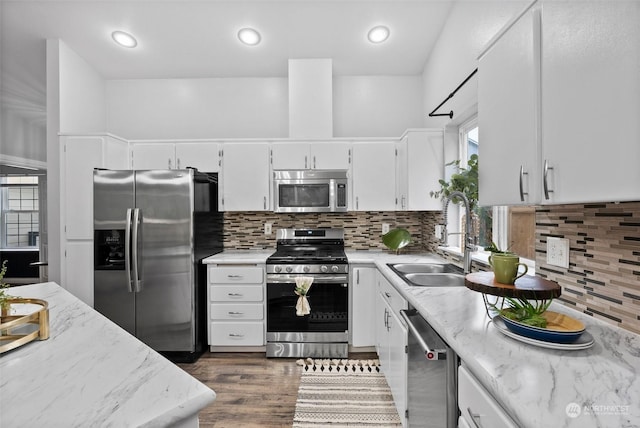 kitchen featuring light stone countertops, decorative backsplash, dark hardwood / wood-style flooring, white cabinets, and appliances with stainless steel finishes