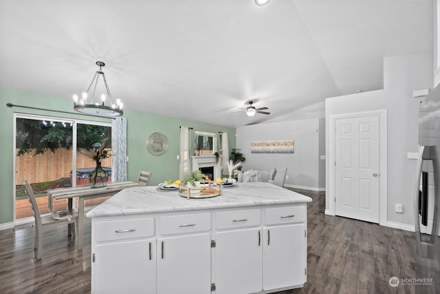 kitchen with a center island, decorative light fixtures, lofted ceiling, white cabinetry, and ceiling fan with notable chandelier