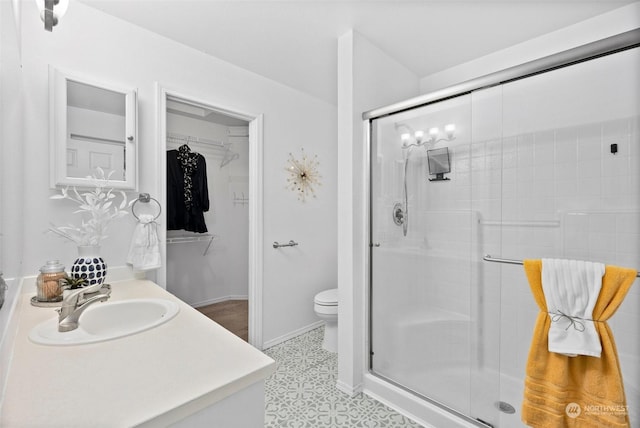 bathroom featuring toilet, tile patterned floors, walk in shower, and vanity