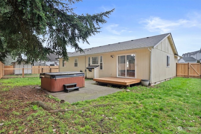 back of house featuring a lawn, a deck, and a hot tub