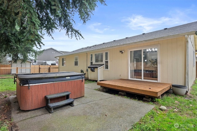 back of property featuring a deck and a hot tub