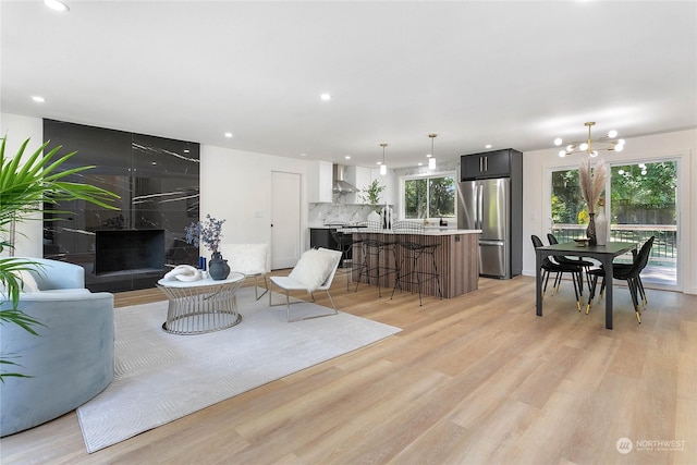 living room with a notable chandelier, a healthy amount of sunlight, and light hardwood / wood-style flooring