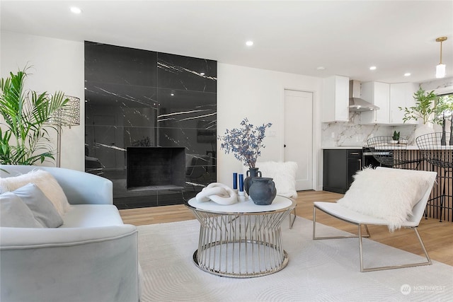 living room with a high end fireplace and light hardwood / wood-style floors