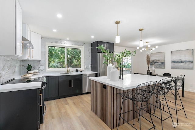 kitchen featuring sink, stainless steel appliances, hanging light fixtures, ventilation hood, and decorative backsplash