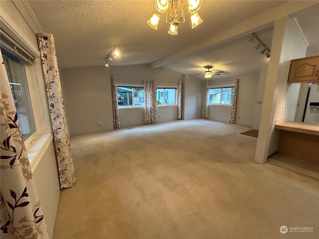 unfurnished living room with lofted ceiling, light carpet, track lighting, ceiling fan with notable chandelier, and a textured ceiling