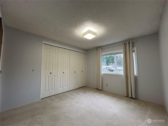 unfurnished bedroom with a textured ceiling, light carpet, and a closet