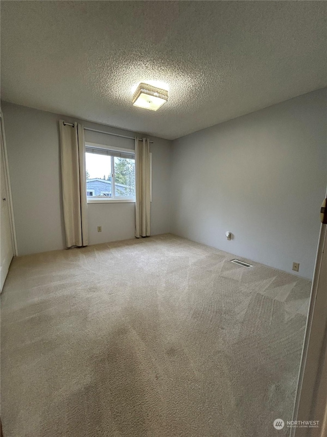 carpeted spare room with a textured ceiling