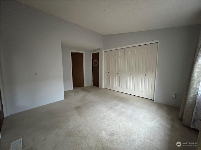 unfurnished bedroom featuring carpet flooring, lofted ceiling, and a closet