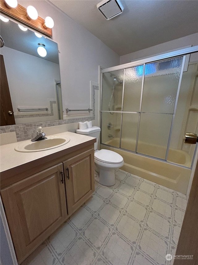 full bathroom with decorative backsplash, toilet, vanity, and combined bath / shower with glass door