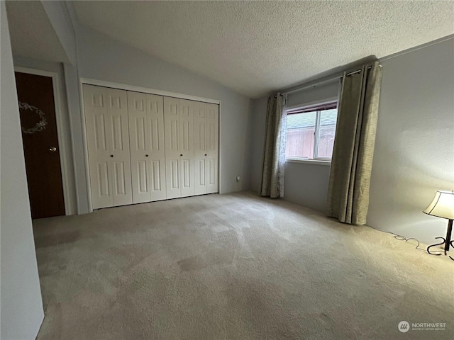 unfurnished bedroom featuring carpet flooring, a textured ceiling, a closet, and lofted ceiling