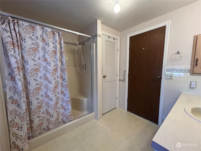 bathroom featuring a shower with shower curtain, vanity, and tile walls