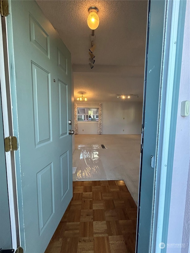 corridor with track lighting and a textured ceiling