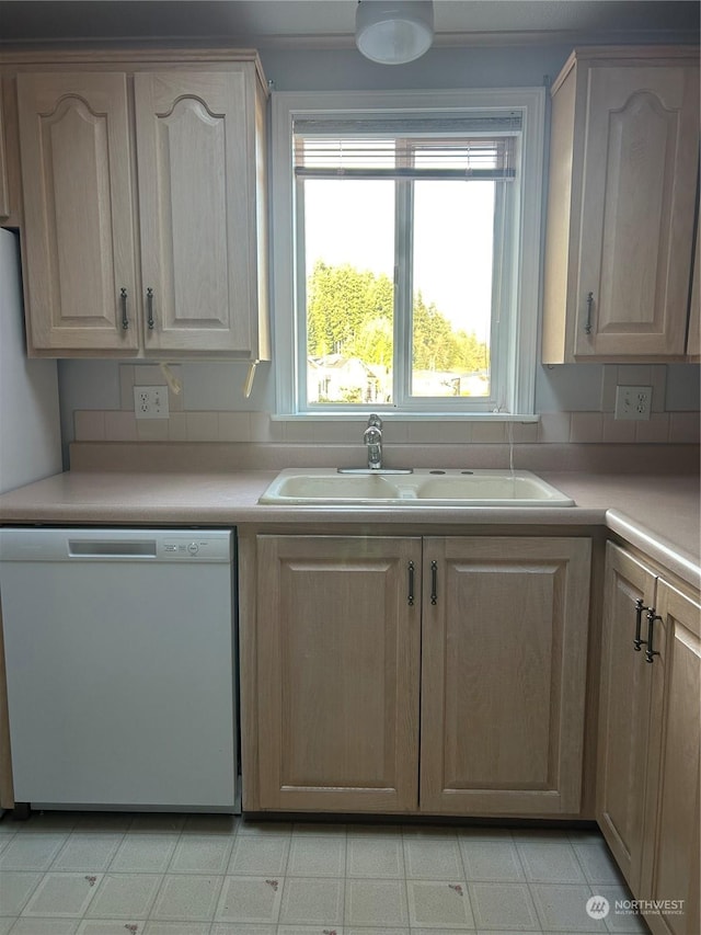 kitchen with sink, white dishwasher, and light brown cabinets