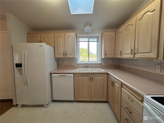 kitchen with light brown cabinets, white appliances, sink, and a skylight