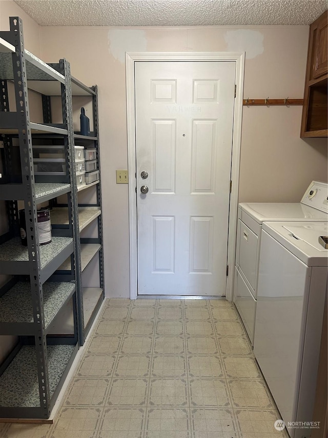 laundry room featuring washing machine and clothes dryer, cabinets, and a textured ceiling