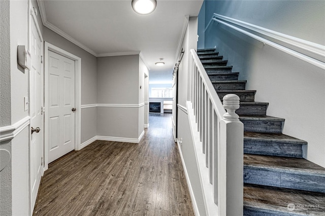 staircase with a fireplace, wood-type flooring, and ornamental molding