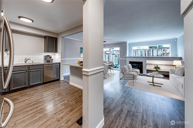 kitchen with hardwood / wood-style floors, tasteful backsplash, stainless steel dishwasher, and crown molding