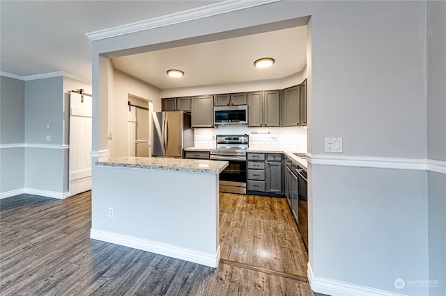 kitchen with stainless steel appliances, a barn door, dark hardwood / wood-style flooring, gray cabinets, and decorative backsplash