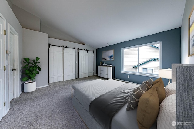 carpeted bedroom featuring a barn door and vaulted ceiling