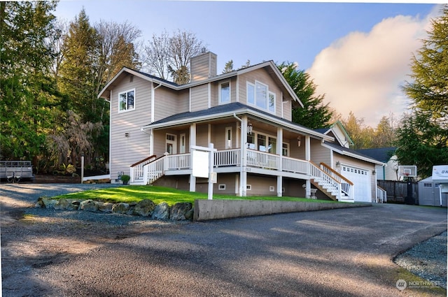 view of front of property featuring a garage, a porch, and a lawn