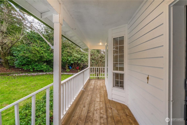 wooden terrace featuring a porch and a lawn