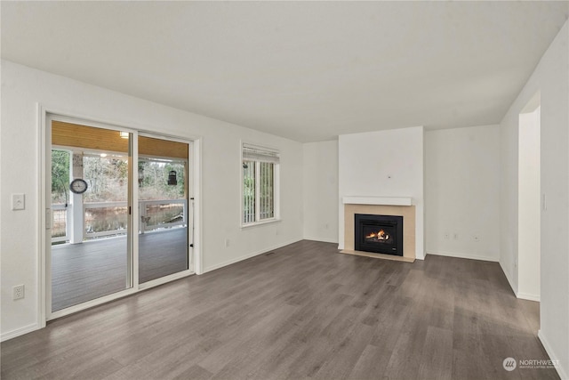 unfurnished living room featuring a tiled fireplace and dark wood-type flooring