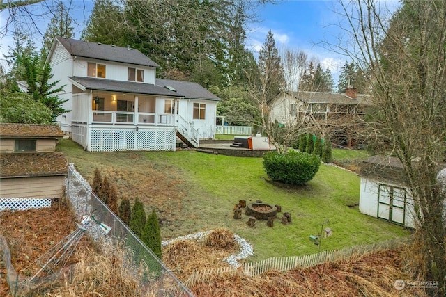 back of property with a storage unit, a yard, and an outdoor fire pit