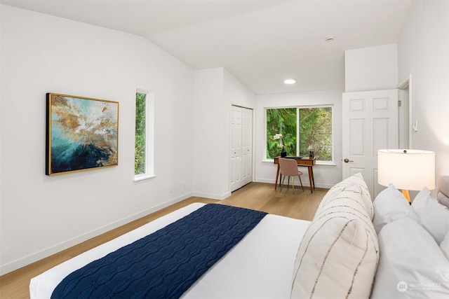 bedroom with lofted ceiling, light hardwood / wood-style flooring, and a closet