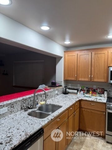 kitchen featuring light stone countertops, stainless steel appliances, and sink