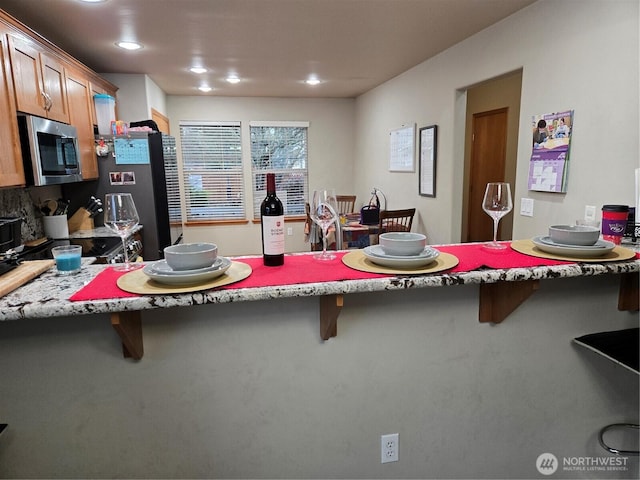 kitchen featuring refrigerator, a kitchen breakfast bar, and kitchen peninsula