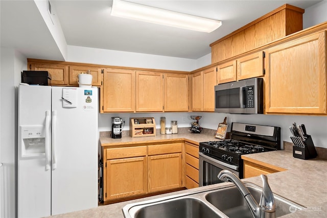 kitchen featuring stainless steel appliances, light brown cabinets, and sink