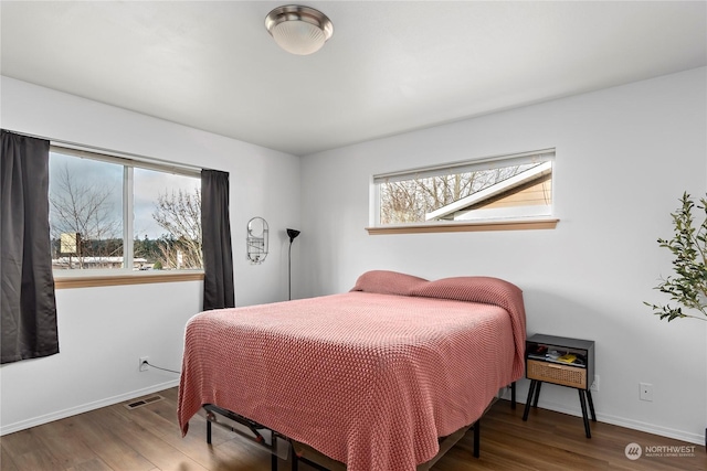 bedroom with dark hardwood / wood-style flooring and multiple windows