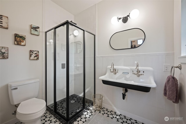 bathroom featuring toilet, a shower with shower door, and sink