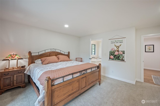 bedroom with ensuite bath and light colored carpet