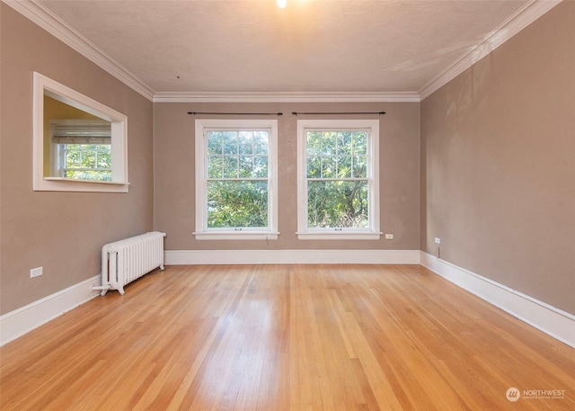 empty room featuring crown molding, radiator heating unit, and light hardwood / wood-style floors