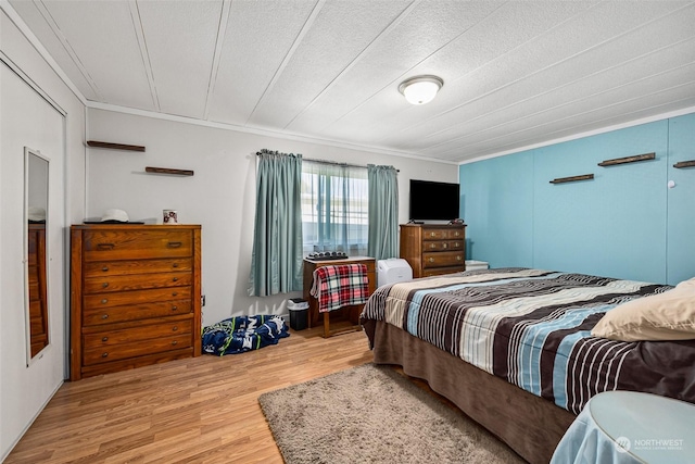 bedroom with crown molding, a textured ceiling, and light wood-type flooring