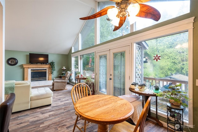 sunroom featuring a tile fireplace, french doors, lofted ceiling with beams, and ceiling fan