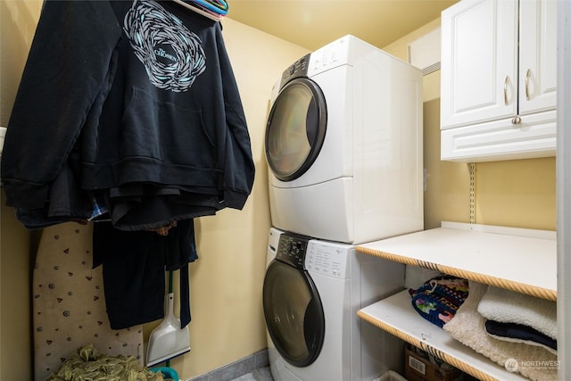 clothes washing area featuring stacked washer and dryer and cabinets