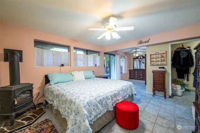 tiled bedroom featuring a wood stove and ceiling fan