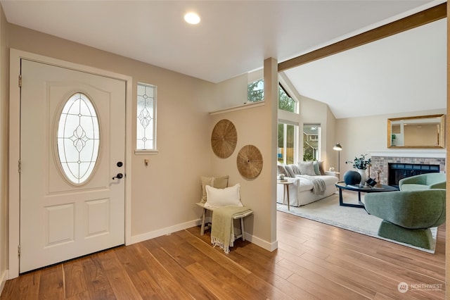 entrance foyer with a fireplace, vaulted ceiling, and wood-type flooring