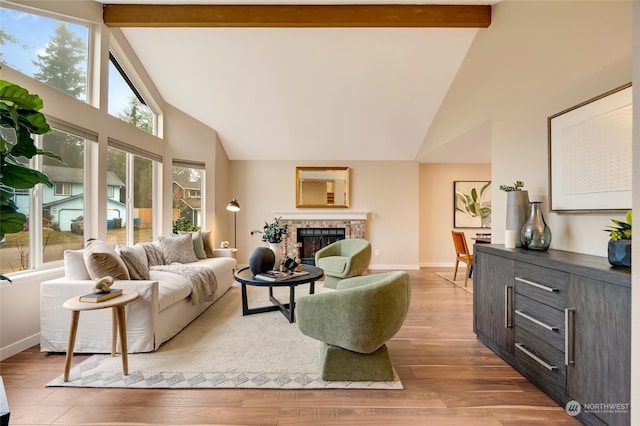 living room with light hardwood / wood-style floors, a wealth of natural light, and vaulted ceiling with beams