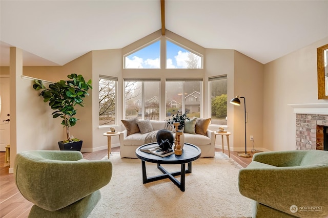 living room with a brick fireplace, lofted ceiling with beams, and light hardwood / wood-style floors