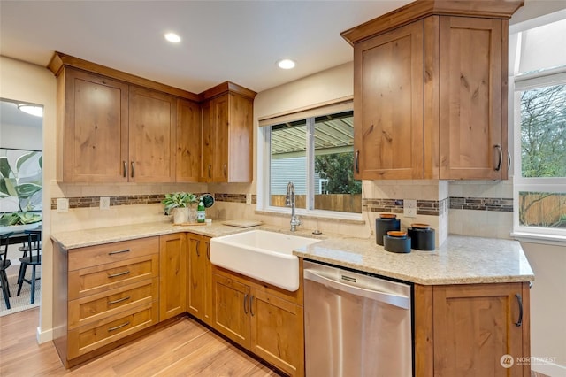 kitchen with dishwasher, light hardwood / wood-style floors, light stone counters, sink, and tasteful backsplash