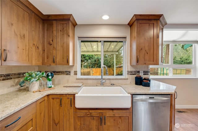 kitchen featuring light stone counters, stainless steel dishwasher, a healthy amount of sunlight, and sink