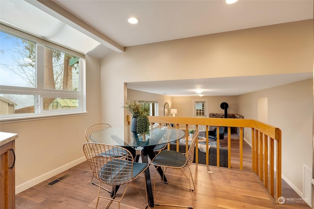 dining area with lofted ceiling with beams and light wood-type flooring