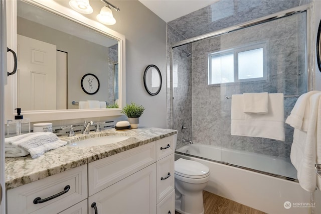 full bathroom featuring shower / bath combination with glass door, toilet, wood-type flooring, and vanity