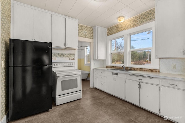 kitchen featuring black fridge, sink, white cabinets, and white electric range oven