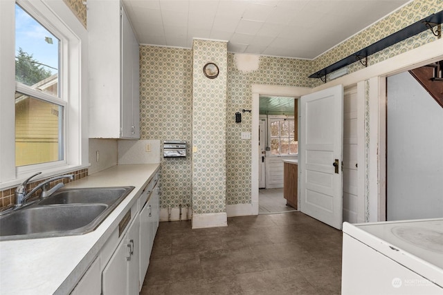 kitchen featuring white cabinetry, sink, plenty of natural light, and range